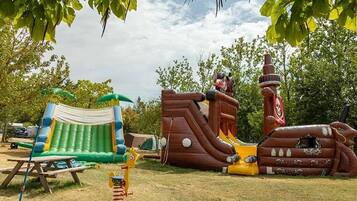 Ein aufblasbarer Spielbereich mit Rutsche, Zelt und Picknicktisch.
