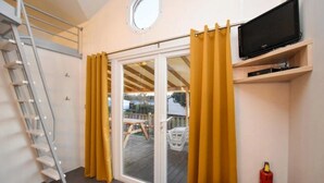 Ein Zimmer mit einer Schiebetür, einem an einer Wandregal montierten Fernseher, einem Feuerlöscher und einer an der Wand stehenden Leiter.