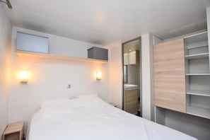 Una habitación de hotel moderna con cama, lámparas de noche, armario y espejo.