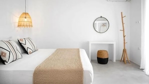 Une chambre à coucher au style minimaliste, avec un lit, une lampe suspendue, un miroir et un porte-manteau en bois.