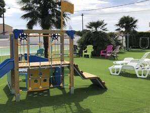 Ein Spielplatz mit einer Kletterkonstruktion, einer Rutsche und einem kleinen Pool.
