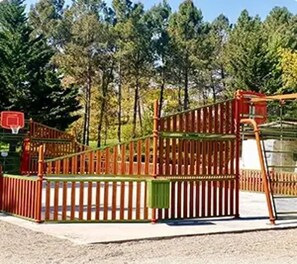 A playground with a wooden climbing structure and a basketball hoop. - Chalet 3 étoiles - ccbgcgi (Gondrin)