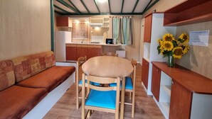A compact living space with a sofa, dining table, chairs, kitchenette, and a small bathroom.