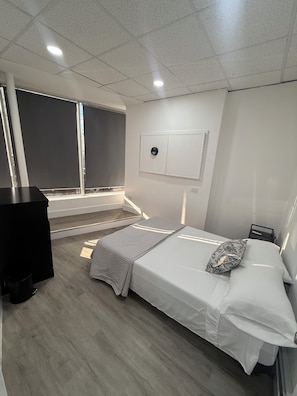 Camera d'albergo moderna con un letto, una scrivania, una finestra e un condizionatore d'aria a parete.