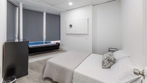 A modern bedroom with a bed, a desk, and a large window. - Spacious 3-bedroom apartment in gorgeous West New York with AC (West New York)