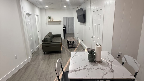 A modern interior with a dining area, sofa, and TV mounted on the wall. - Spacious 3-bedroom apartment in gorgeous West New York with AC (West New York)