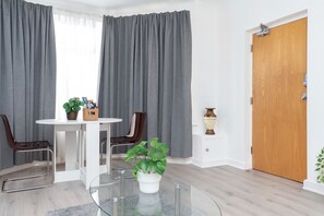 Een moderne kamer met een eettafel, stoelen, een potplant, een houten deur en een witte muur.