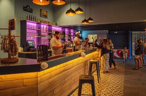 Eine Bar mit Holztresen, Barhocker und einer Auswahl an Flaschen und Gläsern.