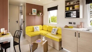 Una cucina compatta con un divano giallo, un tavolo da pranzo con sedie e un forno a microonde.