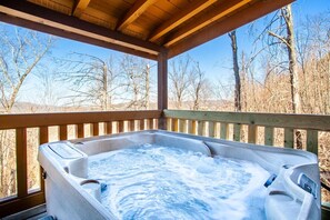 A hot tub on a wooden deck with a view of leafless trees.