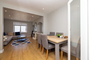 Ein modernes Wohnzimmer mit einer Couch, einem Couchtisch und einem Esstisch mit Stühlen.