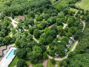 Luftaufnahme einer Wohngegend mit mehreren Häusern, einem Swimmingpool und umgebender Bepflanzung.