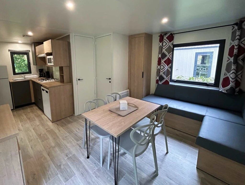 A compact kitchen with a dining area, a built-in oven, and a window with a view.