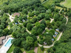 Luftaufnahme einer Wohngegend mit mehreren Häusern, einem Swimmingpool und umgebender Bepflanzung.