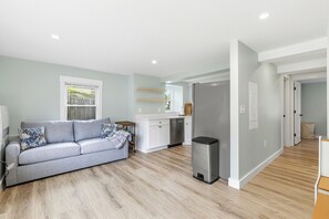 Eine moderne Wohnung mit grauem Sofa, Küchenzeile und Esstisch.