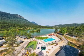 Ein Resort mit Schwimmbad, Tennisplatz und Seeblick, umgeben von Bergen.