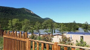 Blick auf einen Ferienort mit mehreren Gebäuden, einem Holzzaun und einem Bergpanorama im Hintergrund.