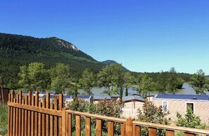 Blick auf einen Ferienort mit mehreren Gebäuden, einem Holzzaun und einem Bergpanorama im Hintergrund.