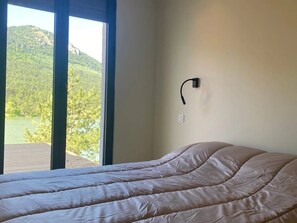 Una cama en una habitación con ventana que da a un área boscosa.