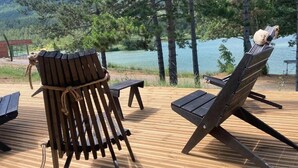 Puisesta laudasta rakennettu terassi, jossa on kaksi Adirondack-tyylistä tuolia järvelle päin, ja terassin ympärillä on puita.