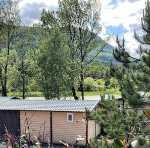 Un bĂątiment dâun seul Ă©tage, dotĂ© dâun toit en tuiles, entourĂ© dâarbres et avec une montagne en arriĂšre-plan.