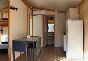 Une cuisine de taille réduite comprenant une table à manger, des chaises, un réfrigérateur et un appareil de climatisation.