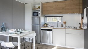 Eine moderne Küche mit weißen Schränken, einem Edelstahlkühlschrank, einem Geschirrspüler und einem Fenster über der Spüle.