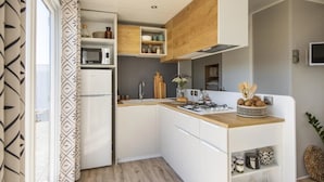 Una cocina compacta con armarios blancos, microondas, lavaplatos y encimera de madera.