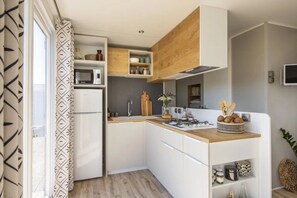 Eine kleine Küche mit weißen Schränken, einer Mikrowelle, einem Spülbecken und einer Holz Arbeitsplatte.