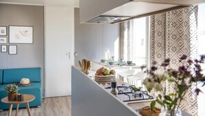 Una cocina moderna con comedor, un sofá azul y una planta decorativa.