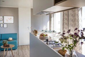 Eine moderne Küche mit Essbereich, einem blauen Sofa und einer Zimmerpflanze.