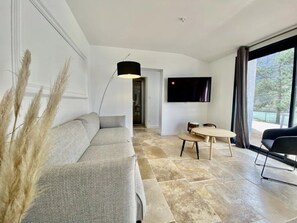 A modern living room with a sofa, a dining table, a TV, and a large window. - Villa 4 étoiles - Piscine  - ccbgbaf (Arques)