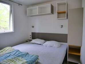Ein Schlafzimmer mit Bett, Fenster und eingebauten Regalen.