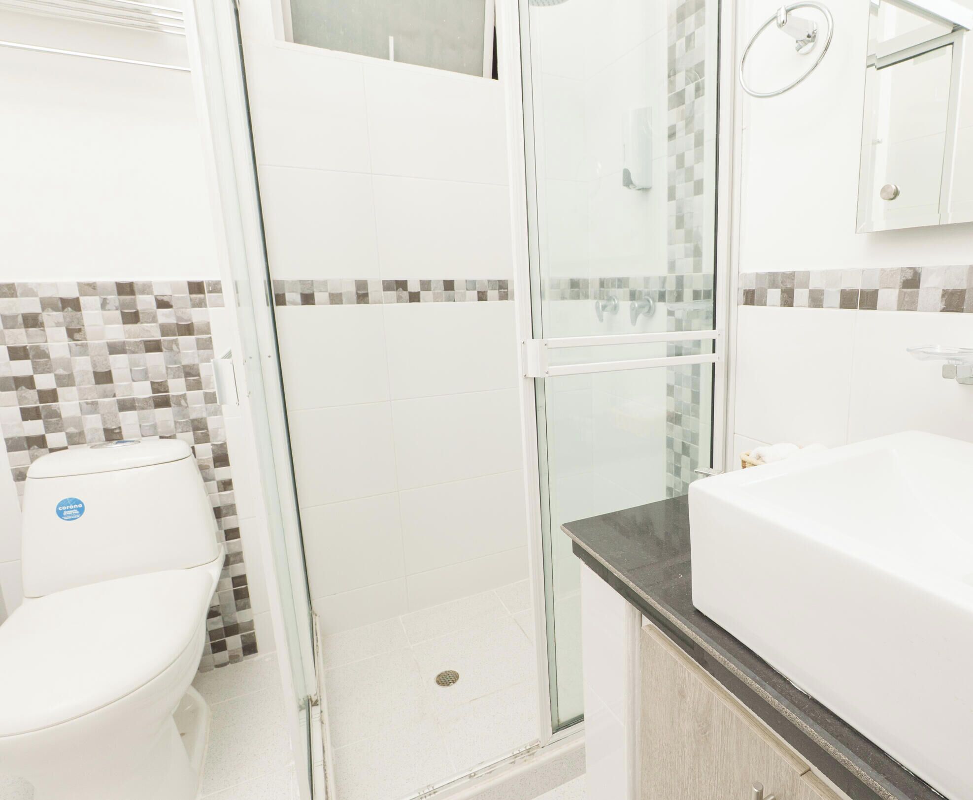 Une salle de bain moderne avec une douche à parois de verre, des toilettes et un lavabo avec un miroir.