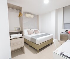 Un dormitorio con cama, mesita de noche, armario, escritorio y una pequeña kitchenette.