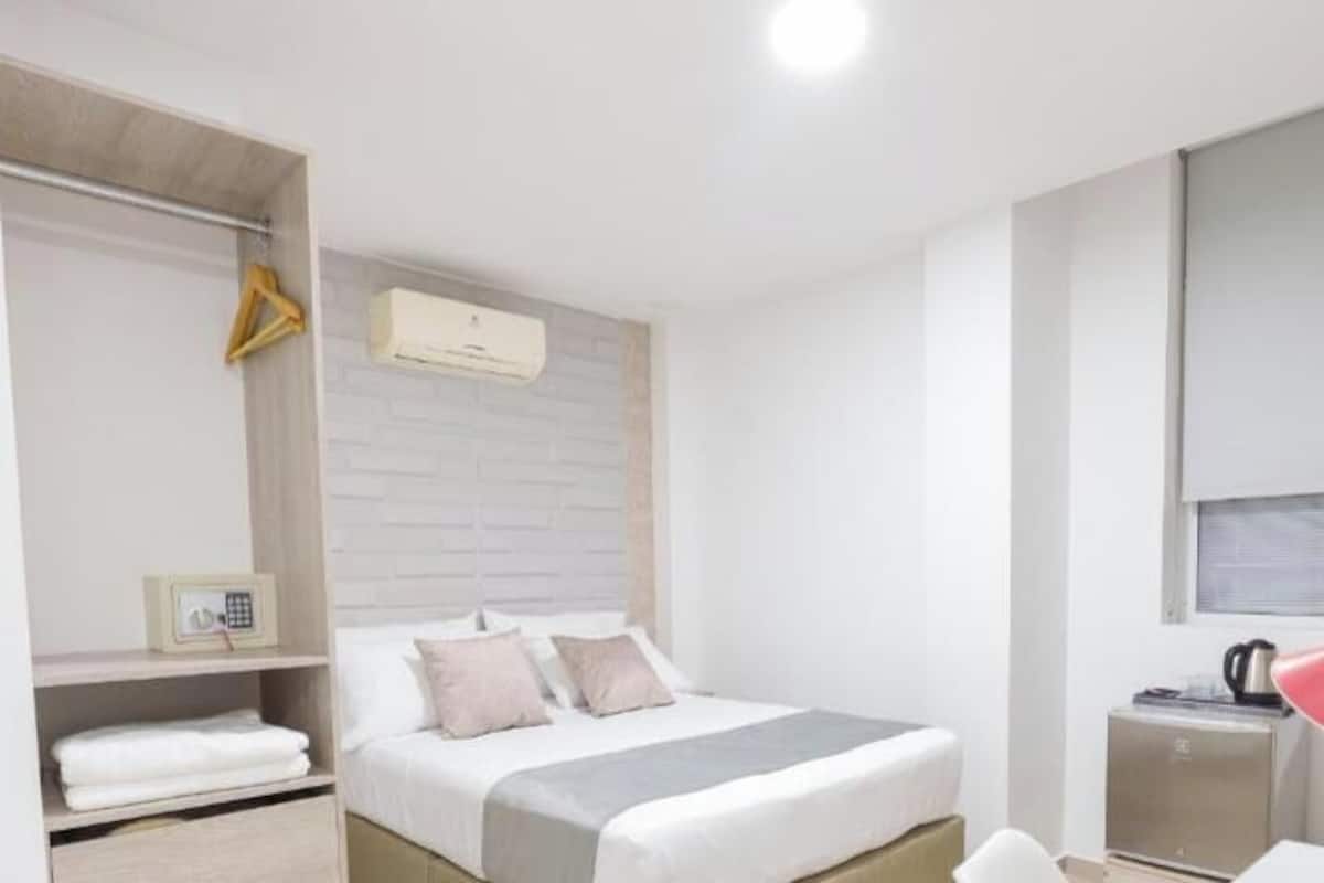 Ein Schlafzimmer mit Bett, Nachttisch, Fernseher, Lampe und Kleiderschrank.