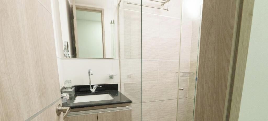 Un baño con lavamanos, espejo y ducha.