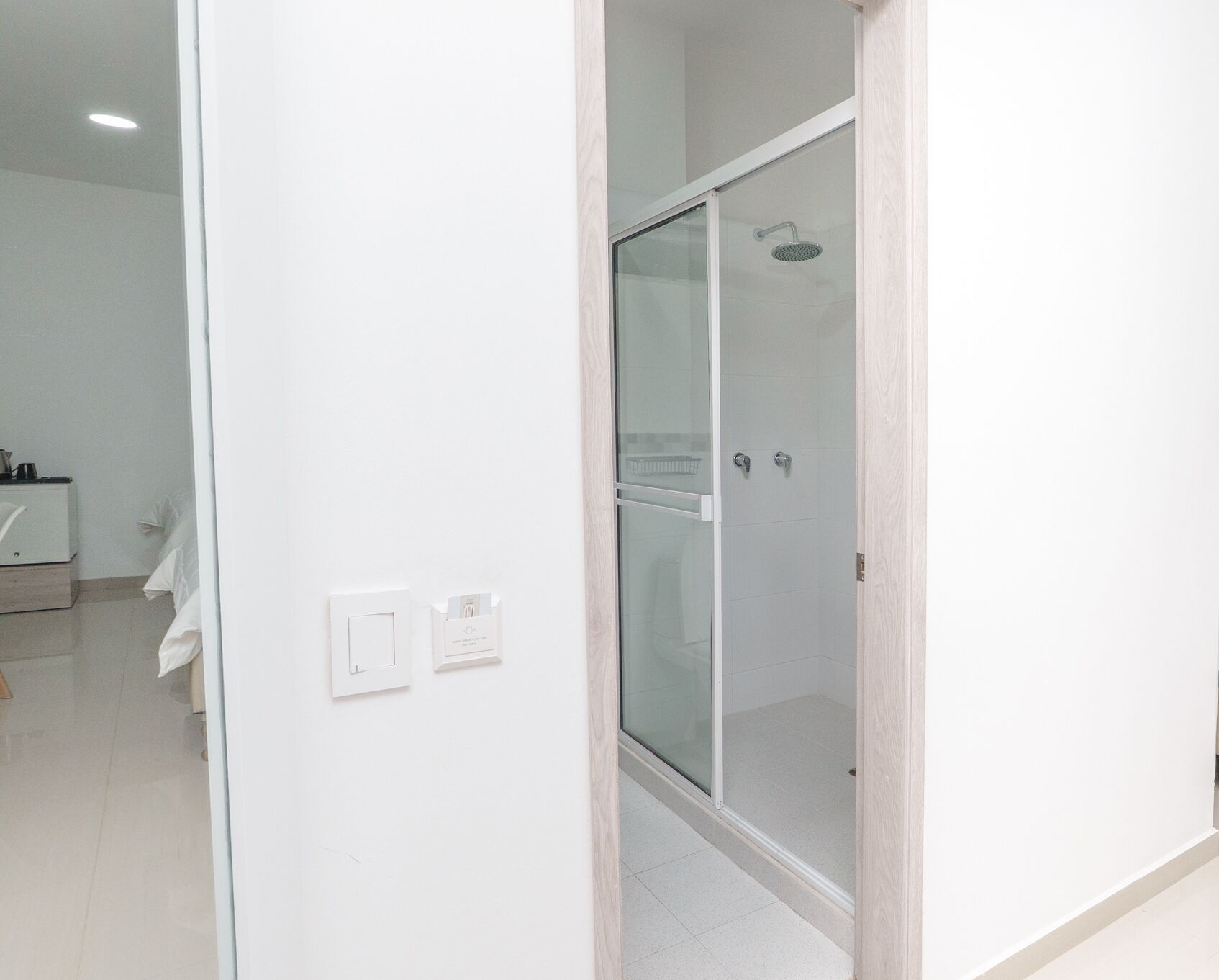 Een moderne badkamer met een glazen douchecabine, een witte wastafel en een toilet.