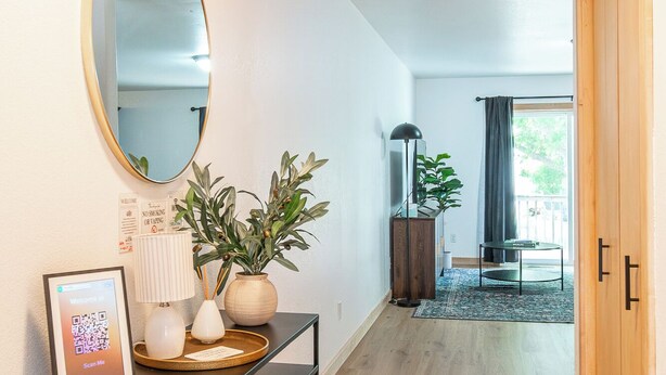 A hallway with a console table, a mirror, a plant, a framed welcome sign, and a view into another room. - 3BR | 7 minutes to Sanford, Fenced Yard, Games (Fargo)