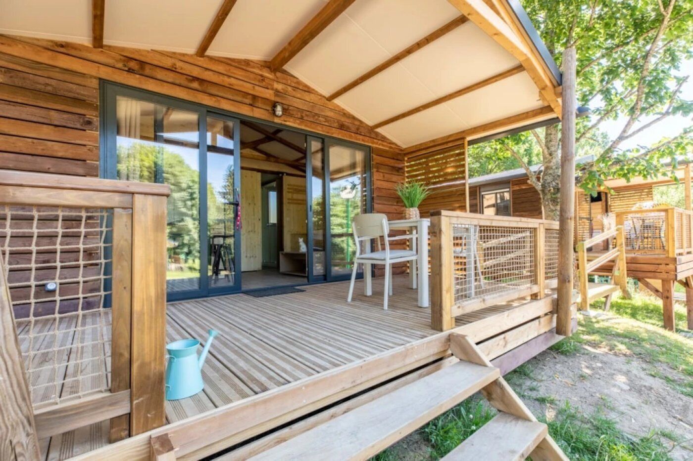 A wooden deck with a glass door leading to a room, a chair, a small table, and a plant.