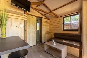 En inredning med träpanel, en soffa, ett litet bord, en tv och ett fönster.