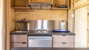 A compact kitchen with a stainless steel dishwasher, a coffee maker, and wooden cabinets. - Chalet 3 étoiles - ccbgcfc (Saint-Bonnet-près-Orcival)