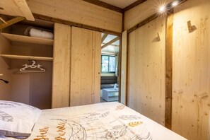 Ett rum med träpanel, en säng, en hängande lampa och ett fönster.