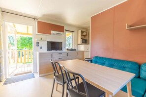 A compact kitchen with a dining area, a microwave, and a view of the outdoors. - Camping 3 étoiles - ccbgcfd (Saint-Bonnet-près-Orcival)