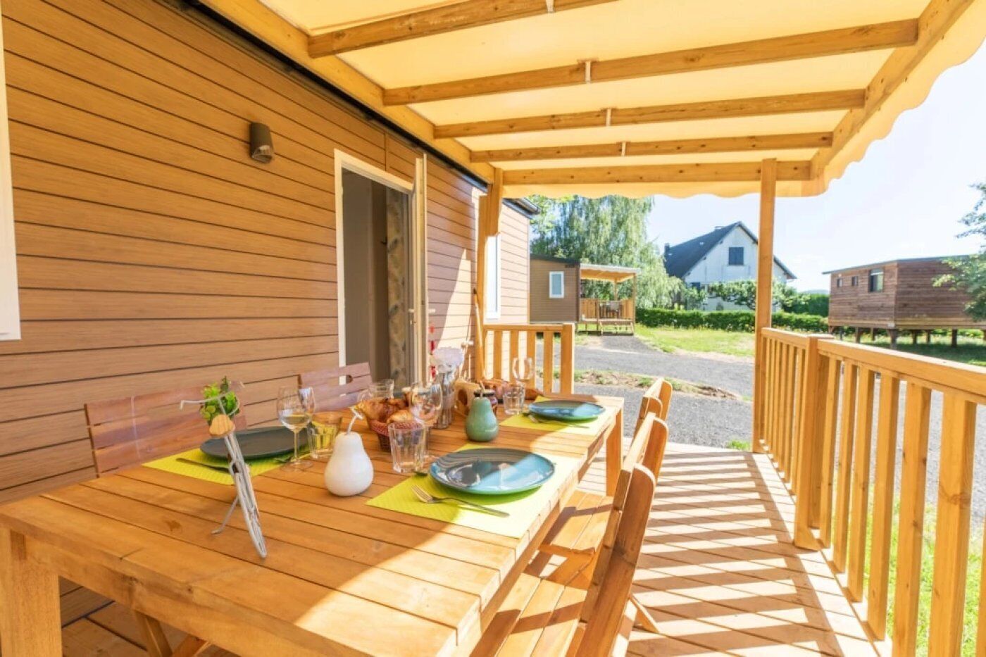A wooden deck with a table set for dining, a covered area, and a view of a rural landscape.