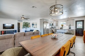 A modern living room with a wooden dining table, sofa, and a TV. - Pet-Friendly Scottsdale Retreat w/ Pool & Hot Tub (Scottsdale)