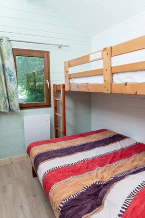 Uma cama beliche com escada, uma janela com cortinas e um edredom estampado.