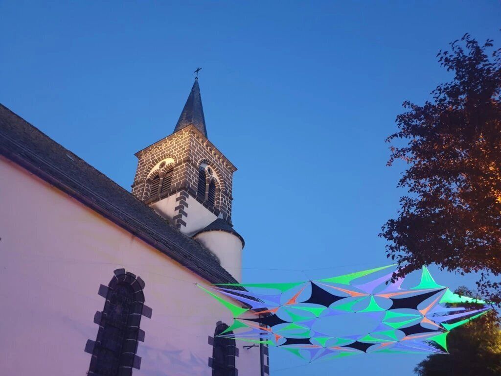 A church with a prominent steeple and a geometric light installation.