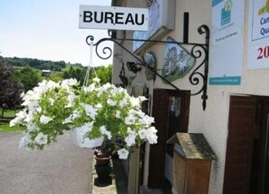 A building with a sign reading 'BUREAU' and a hanging flower basket. - Chalet 3 étoiles - ccbgcff (Saint-Bonnet-près-Orcival)