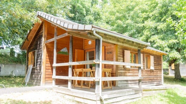 Eine Holzhütte mit Veranda, Tisch und Stühlen.